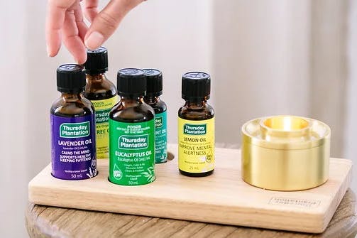 A hand reaching across four bottles of essential oils.